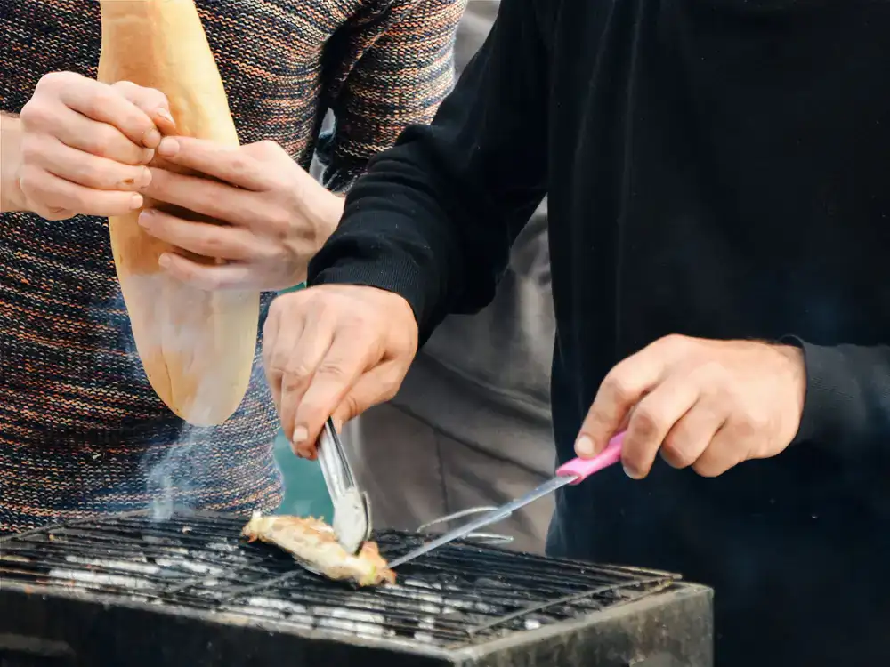 Chef carefully turning fish on a hot grill